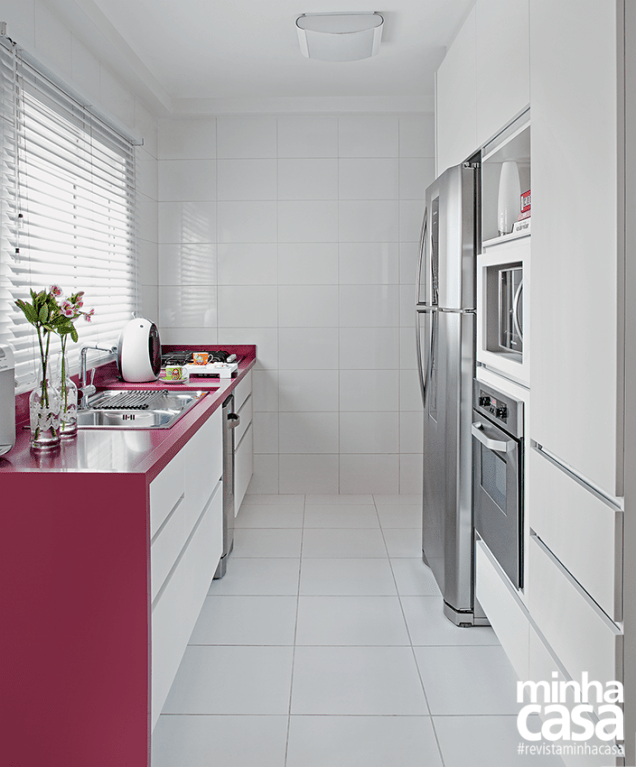 A bancada de Silestone em tom de magenta e dá vida ao ambiente branco desta linda cozinha. Projeto da <span>arquiteta Andréia Karalkovas.</span>