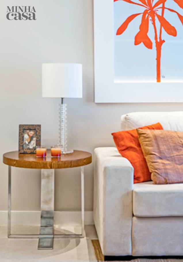 "Em geral, costumo especificar uma mesa que tenha a mesma altura do braço do sofá para que os objetos sobre ela apareçam", afirma o arquiteto Luiz Fernando Grabowsky, do estúdio carioca que leva seu nome. A preferência é exemplificada com um de seus projetos: alinhado com a lateral do estofado, o móvel (65 x 60 cm, de aço inox e MDF com acabamento no padrão carvalho) põe em destaque o porta-retratos, o abajur e os porta-velas. O tampo redondo de madeira ajuda a aquecer o ambiente juntamente com os tons vermelhos do quadro e das almofadas. "Em geral, costumo especificar uma mesa que tenha a mesma altura do braço do sofá para que os objetos sobre ela apareçam", afirma o arquiteto Luiz Fernando Grabowsky, do estúdio carioca que leva seu nome. A preferência é exemplificada com um de seus projetos: alinhado com a lateral do estofado, o móvel (65 x 60 cm, de aço inox e MDF com acabamento no padrão carvalho) põe em destaque o porta-retratos, o abajur e os porta-velas. O tampo redondo de madeira ajuda a aquecer o ambiente juntamente com os tons vermelhos do quadro e das almofadas.