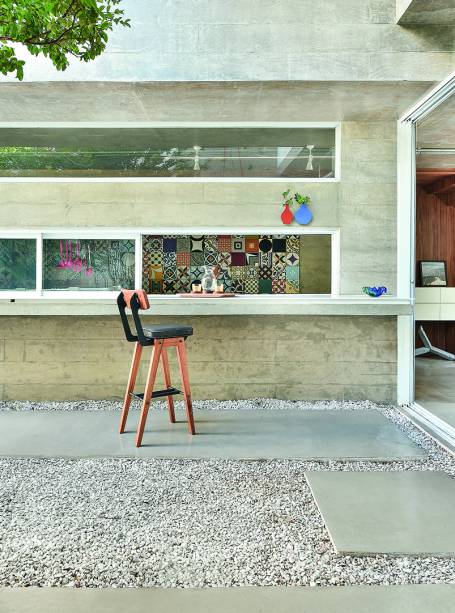 Concreto, azulejo e outros elementos que fizeram história na arquitetura brasileira ajudaram a dar forma à casa projetada pelo arquiteto Luiz Paulo Andrade. Do lado externo, réguas de concreto feitas na obra com pranchas de madeira desenham as paredes, lixadas para ganhar aspecto manchado. “Uma camada de óleo hidrofugante serviu para selar a superfície e protegê-la da água”, explica o profissional. A mesma matéria-prima em placas cimentícias retangulares demarca o caminho sobre os pedriscos.