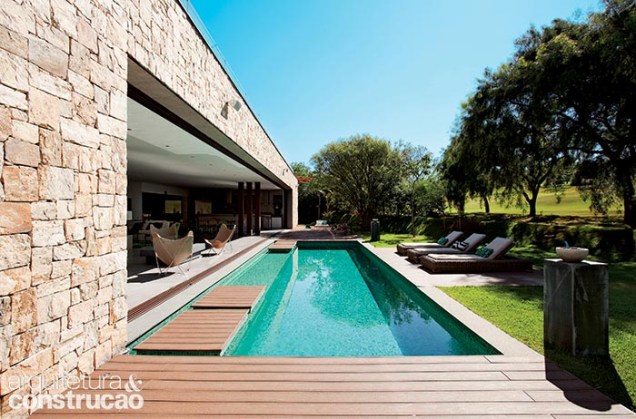 Esta foto revela a extensão de mais de 20 m do vão da sala. Com 3,80 x 7 m, a piscina leva plaquetas de 20 x 20 cm de pedra hijau (Palimanan). Perto do estar, surgem as pisadas flutuantes revestidas com o mesmo deck plástico (Allpex Madeira Plástica) de toda a área externa. Esta foto revela a extensão de mais de 20 m do vão da sala. Com 3,80 x 7 m, a piscina leva plaquetas de 20 x 20 cm de pedra hijau (Palimanan). Perto do estar, surgem as pisadas flutuantes revestidas com o mesmo deck plástico (Allpex Madeira Plástica) de toda a área externa.