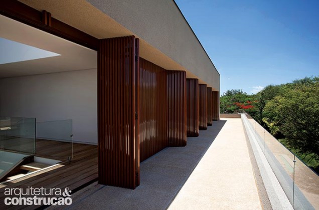 No primeiro pavimento, o terraço passeia por todos os dormitórios, oferecendo visão privilegiada do panorama. O fechamento é um brise inteiriço, de ponta a ponta, de alumínio com pintura de efeito madeira (Metal-Lar).