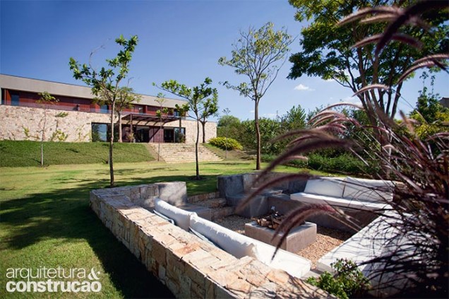 Ao instalar a construção no ponto mais alto do lote, o projeto conquistou melhor vista para todos os ambientes. Nas noites frias, este recanto ao ar livre conta com o calor da lareira, ao centro.