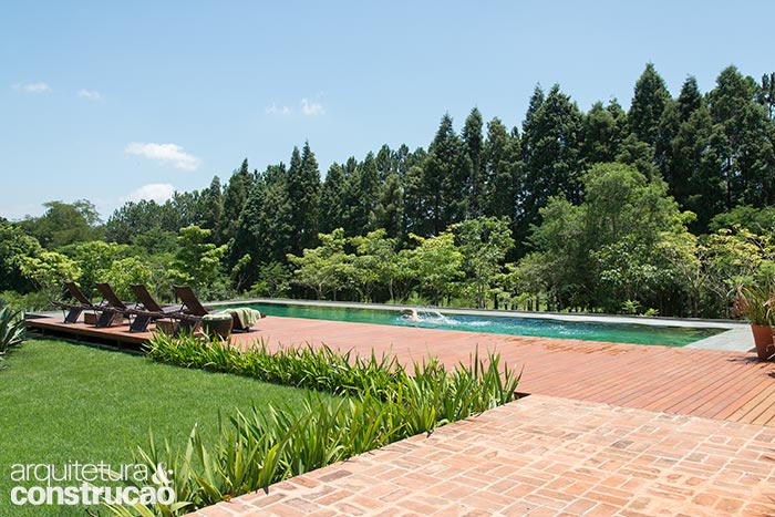 Um caminho de tijolos interliga a varanda ao deck de cumaru junto à piscina.