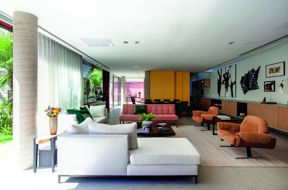 Na casa toda (com exceção dos quartos), o piso emprega limestone. No térreo, dois dos pilares metálicos que estruturam os andares superiores se inserem em cilindros de concreto – um acabamento mais discreto, já que no resto os elementos de aço receberam pintura vermelha. Ao fundo, à esq., situa-se a entrada social.