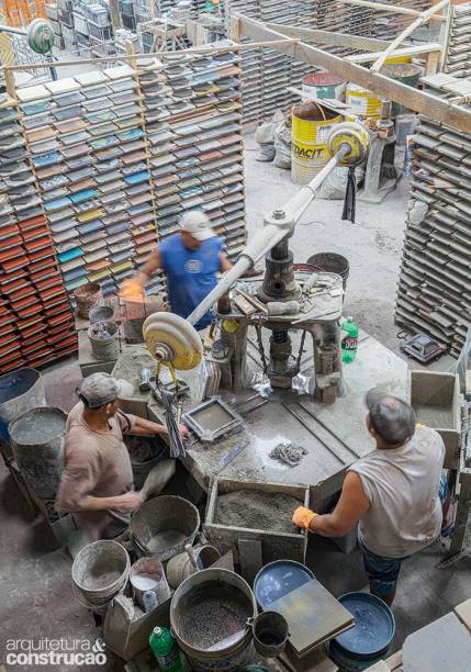 O galpão reúne seis estações de produção como esta, da prensa manual. Depois de passar por essa etapa, a placa repousa até ser colocada no tanque para a cura.