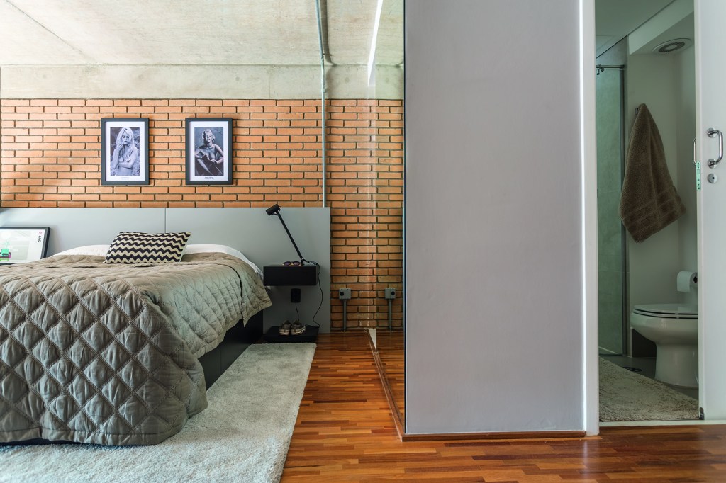 Quarto; parede de tijolinhos; piso de madeira; tapete; cama de casal