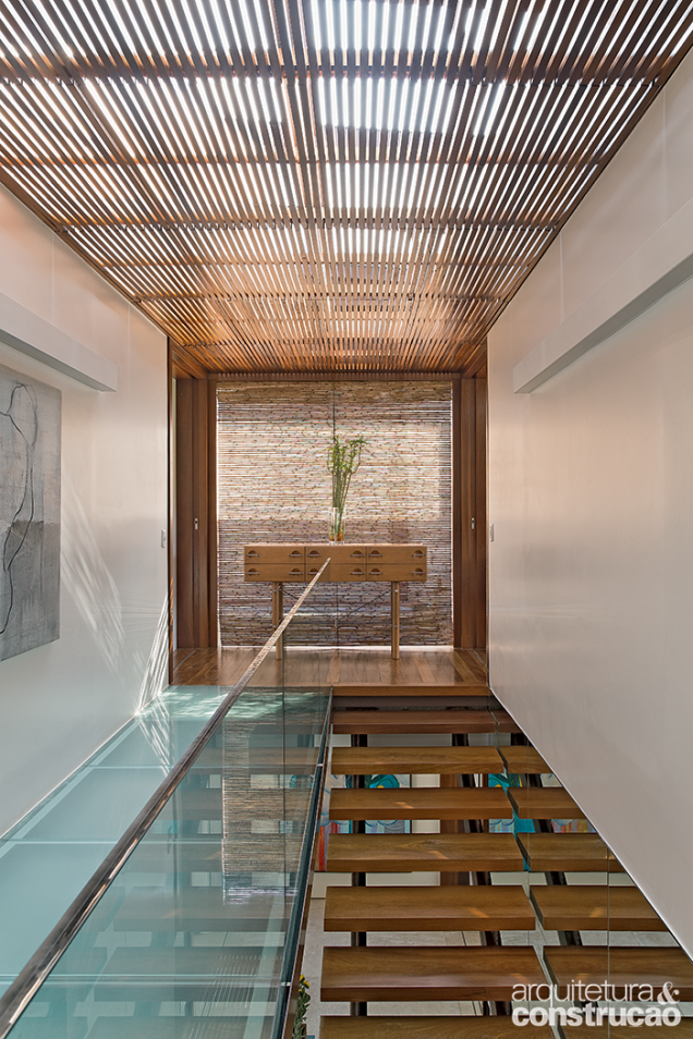 O telhado de vidro levemente inclinado banha de luz natural a escada e a passarela também envidraçada do andar superior.