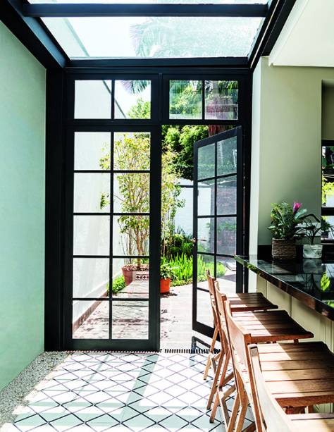 Ao repaginar o sobrado dos anos 30, as profissionais da In House Designers de Interiores acrescentaram elementos com estilo industrial e um quê de nostalgia. É o caso das portas de ferro pintadas de esmalte preto que, juntamente com a cobertura do mesmo material, deixam a luz do jardim chegar à cozinha. “O desenho reto da peça e o quadriculado dos vidros combinam bem com a linguagem da construção”, explica a designer de interiores Betina Barcellos. Com abertura tradicional e dobradiças rudimentares, as folhas (0,81 x 2,20 m cada uma) foram confeccionadas pela Serralheria Lombardo.