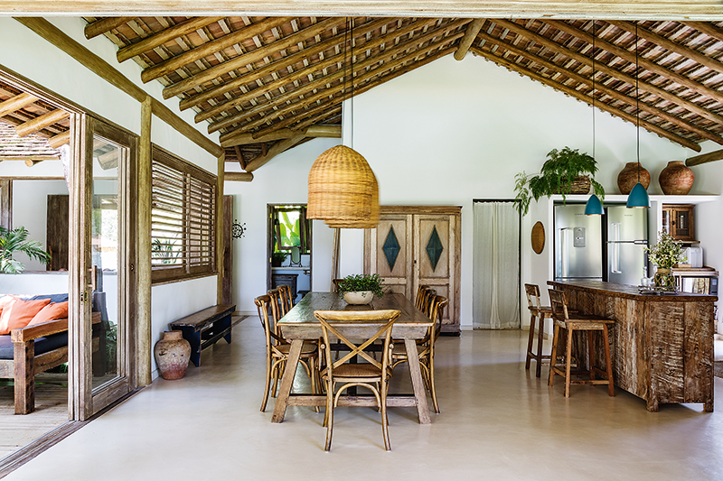 Generoso, este espaço abriga a cozinha e a sala de jantar. “Melhor fazer uma única estrutura, bem completa, do que criar outro ambiente para a varanda gourmet”, fala a arquiteta. No teto sem forro, está aparente o verso das taubilhas. No piso, cimento queimado feito na obra. Projeto: Cris Nogueira.