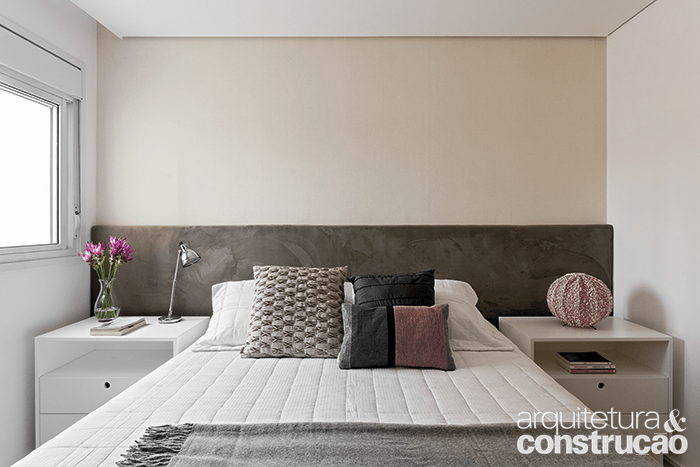 No quarto do casal, a cama tamanho queen é acompanhada pelo painel estofado e revestido de camurça. As mesas de cabeceira desenhadas pelo arquiteto exibem acabamento de laca branca. Almofadas e vasos da Dpot Objetos.