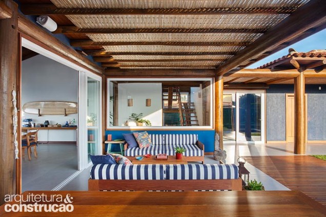 Entre o estar e o pátio interno, a área gourmet reúne churrasqueira e forno a lenha sob teto de vidro com forro de fibra de bambu.
