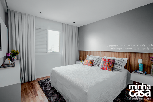 <span>A elegante solução para a cabeceira foi conquistada graças à aplicação de laminado melamínico no padrão nogueira até metade da parede. Logo acima, os arquitetos instalaram um painel de MDF que avança 10 cm em direção à cama. Ele foi laqueado de cinza e recebeu um adesivo. Uma fita de LED foi aplicada na base a fim de que o ambiente ganhasse uma luz cênica e aconchegante. “É um detalhe que cria um efeito e tanto!”, ressalta Iedda. </span>Projeto dos arquitetos Alessandro Nicolaev e Iedda Oliveira - Cor da parede – Papel Machê, ref. R208, da Suvinil <span>A elegante solução para a cabeceira foi conquistada graças à aplicação de laminado melamínico no padrão nogueira até metade da parede. Logo acima, os arquitetos instalaram um painel de MDF que avança 10 cm em direção à cama. Ele foi laqueado de cinza e recebeu um adesivo. Uma fita de LED foi aplicada na base a fim de que o ambiente ganhasse uma luz cênica e aconchegante. “É um detalhe que cria um efeito e tanto!”, ressalta Iedda. </span>Projeto dos arquitetos Alessandro Nicolaev e Iedda Oliveira - Cor da parede – Papel Machê, ref. R208, da Suvinil