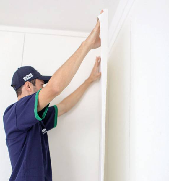 6. Comece a instalação pelo alto à esquerda, pautando-se pela linha de prumo. Abra a primeira dobra  do papel, fixe-a deixando 10 cm além da linha do teto e vá desdobrando e colando até o rodapé.
