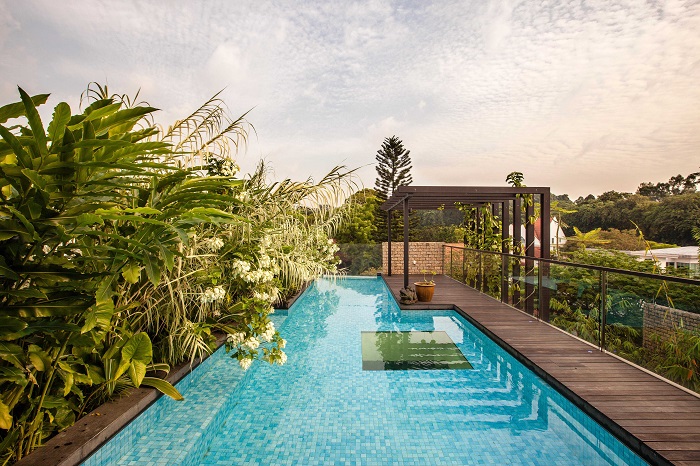 Um deck de madeira emoldura a piscina nas laterais. O quadrado, ao centro, não leva revestimento – quem o vê do térreo consegue observar a água através do vidro.