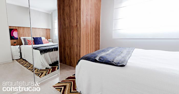 A alvenaria entre quarto e sala veio abaixo, trocada pelo guarda-roupa do piso ao teto. Deste lado, as portas espelhadas ajudam na percepção de amplitude. Na face voltada para a ala social, o móvel serve de painel de TV.