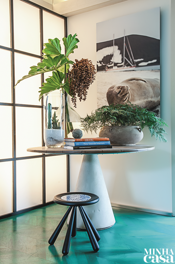 Com projeto de Fabio Basani e Tulio Xenofonte, o Living da Família foi idealizado para moradores que gostam de velejar – daí a ideia de evocar a natureza nos detalhes. Aqui, a mesa rústica apoia vasos de plantas, e o piso de madeira ostenta pintura verde-esmeralda.