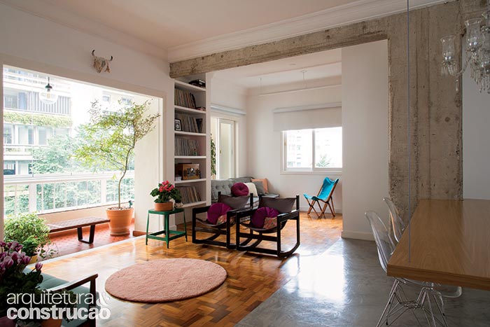 Um dos quartos se incorporou à sala. Sumiram as paredes, e a estrutura ficou à vista. A varanda recebeu painéis de vidro (Solarlux) sobre o peitoril, e a esquadria que a isolava da sala saiu de cena, ampliando a área social. Maltratados pelo tempo, os tacos foram lixados e depois protegidos com resina à base de água. As peças sem salvação deram vez a algumas retiradas do ambiente vizinho, que repete o chão da cozinha.Na área de refeições,  o cimento queimado  substitui o piso de madeira. A mudança mais marcante da reforma aposta nos tons de concreto.
