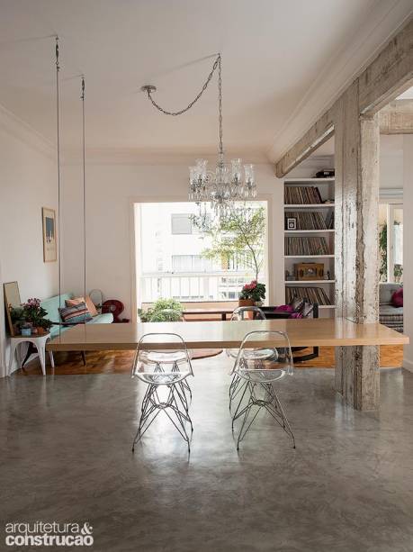 Cozinha, sala e varanda abertas são palco para as reuniões promovidas pelo casal de publicitários. A morada tem o jeito dos dois: o lustre de cristal dela (herdado da avó, passou por um restauro na Oficina dos Lustres) convive bem com os vinis dele, acomodados na estante. A mesa suspensa carvalho americano apoia-se em cantoneiras fixadas no pilar; do outro lado, ela se prende ao teto por cabos de aço. Desenho da arquiteta Luciana Castro.