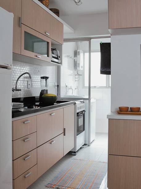 <span>O espaço recebeu mobiliário desenhado sob medida pelo arquiteto. Nos novos gabinetes e módulos suspensos – produzidos em MDF com revestimento laminado -, louças e mantimentos podem ser acomodados com folga. Repare que, acima dos armários, o arquiteto Daniel Tesser projetou uma prateleira que é usada para exibir objetos.</span> <span>O espaço recebeu mobiliário desenhado sob medida pelo arquiteto. Nos novos gabinetes e módulos suspensos – produzidos em MDF com revestimento laminado -, louças e mantimentos podem ser acomodados com folga. Repare que, acima dos armários, o arquiteto Daniel Tesser projetou uma prateleira que é usada para exibir objetos.</span>