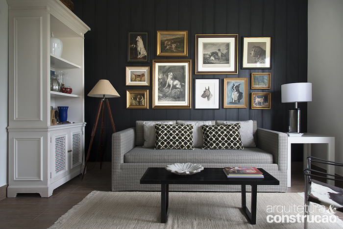 O MDF preto se repete na parede da sala, decorada com diversos quadros.
