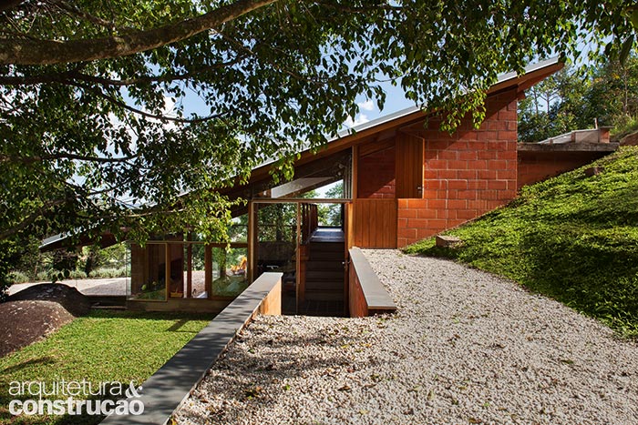 A construção encaixa-se na encosta, deixando área plana livre para a convivência a céu aberto. Note que o telhado segue a inclinação da montanha, capricho planejado ainda na avaliação do terreno.