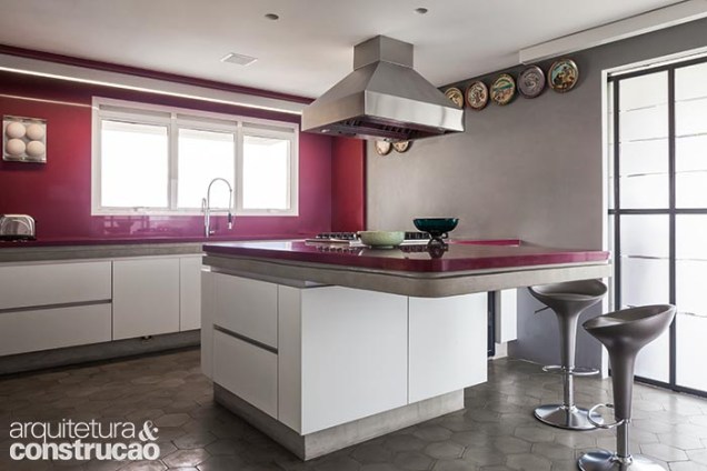 O Silestone magenta (SLF Mármores) destaca-se na cozinha predominantemente cinza. Com seu tom chamativo, presente na ilha, na bancada e na parede da pia, o material dialoga com o piso multicolorido da área social.