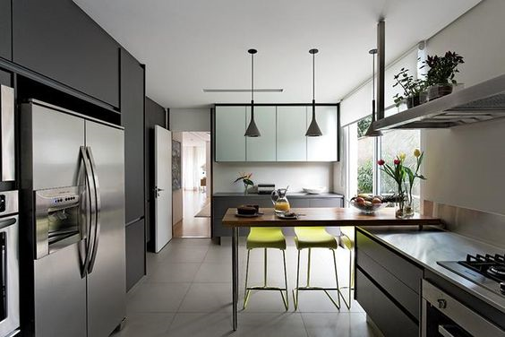 Laminado melamínico na cor chumbo e vidro acidado revestem os armários da cozinha (Kitchens), construída no andar térreo. A coifa (Tuboar) e os tampos (Mekal) são de aço inox