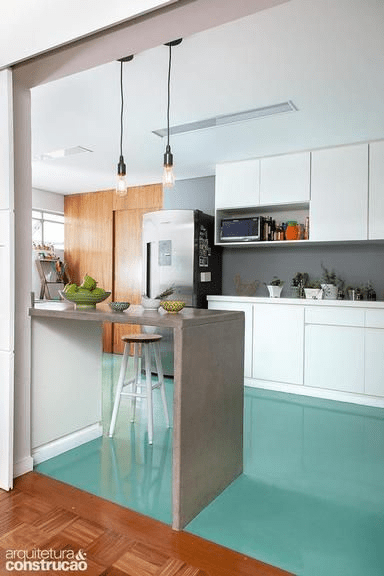 Antes convencional, o ambiente passou a ser integrado e recebeu nova roupagem para ficar à vista na proposta da Roberta Rinaldi e Flavia Terran, do escritório Ter Arquitetura. O piso de epóxi verde-água, executado pela RLX Pinturas com material da Tintas Ancora, uniformiza o espaço. “Esse revestimento é muito prático, e seu tom compõe bem com o taco da sala”, explica Flávia. As paredes receberam pintura cinza (Suvinil, ref. Elefante, D161).