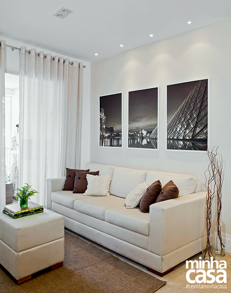 Sala de estar pequena com sofá branco e três fotos acima do sofá