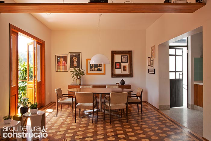 A única delimitação entre sala de jantar, de estar e cozinha são os pisos originais e o granilite (novo, porém respeitando os tons daquele que existiu ali). O acesso à garagem, no térreo, se dá pela escada atrás da porta de ferro (à dir.), feita sob medida e inspirada num modelo que o casal viu em Nova York. A única delimitação entre sala de jantar, de estar e cozinha são os pisos originais e o granilite (novo, porém respeitando os tons daquele que existiu ali). O acesso à garagem, no térreo, se dá pela escada atrás da porta de ferro (à dir.), feita sob medida e inspirada num modelo que o casal viu em Nova York.