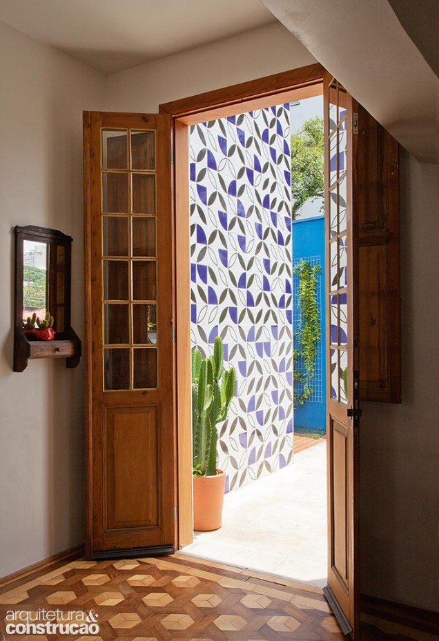 “Tivemos que adaptar a parede para acomodar esta porta antiga, que encontramos antes de comprar a casa”, conta a proprietária. Azulejos da Lurca marcam a entrada principal com acesso para o jardim.