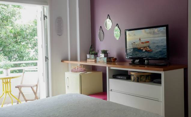 <span>Na frente da cama, a parede da TV se enfeitou com um tom rosado e um kit de espelhos decorativos. A bancada que sustenta o aparelho é um tampo de MDF, recortado conforme os desníveis da alvenaria vizinha, que se apoia na antiga cômoda e vai aparafusado na extremidade. Dessa forma, criou-se um nicho para o frigobar retrô, sonho de consumo do casal. Decorado pela blogueira e decoradora carioca Vivi Visentin, do blog Decorviva.</span> <span>Na frente da cama, a parede da TV se enfeitou com um tom rosado e um kit de espelhos decorativos. A bancada que sustenta o aparelho é um tampo de MDF, recortado conforme os desníveis da alvenaria vizinha, que se apoia na antiga cômoda e vai aparafusado na extremidade. Dessa forma, criou-se um nicho para o frigobar retrô, sonho de consumo do casal. Decorado pela blogueira e decoradora carioca Vivi Visentin, do blog Decorviva.</span>