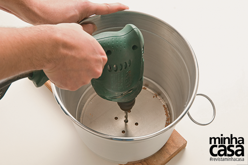 1. Usando uma tábua como apoio, faça um furo central na base do balde e outros quatro ao redor - eles deixam o ar quente sair quando a lâmpada está acesa. 1. Usando uma tábua como apoio, faça um furo central na base do balde e outros quatro ao redor - eles deixam o ar quente sair quando a lâmpada está acesa.