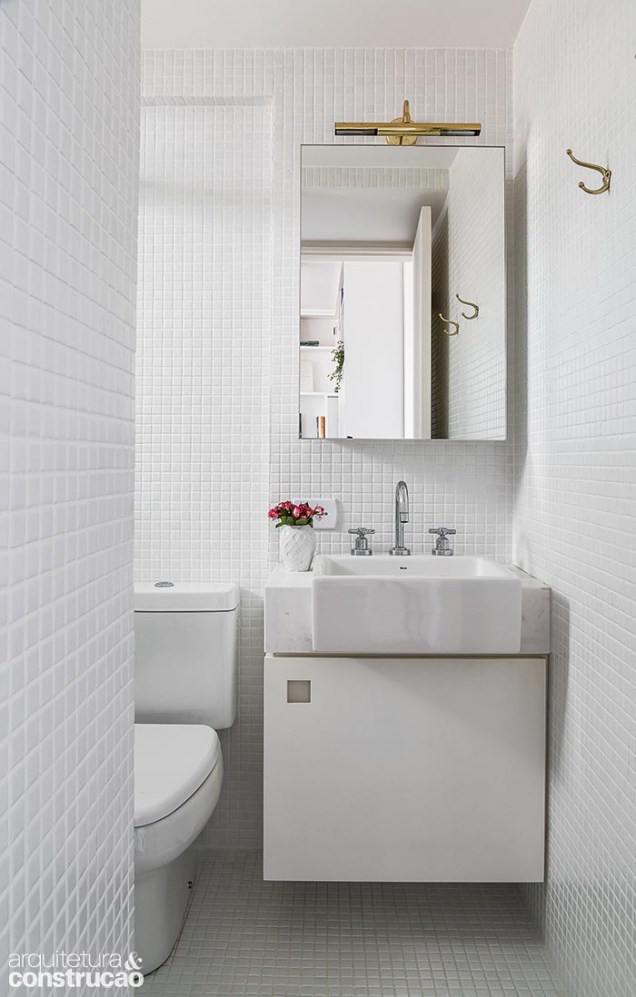 O branco também predomina no banheiro, que tem o mesmo acabamento da lavanderia, além de pia de mármore piguês e armário com pintura gofrato.