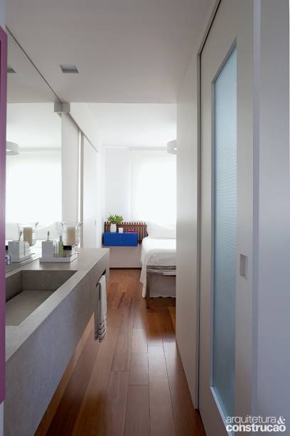 O quarto da moradora ganhou feições de suíte com a incorporação do banheiro, fechado pela porta translúcida de correr de vidro aramado. A fim de ampliá-lo internamente, o projeto transferiu a pia para fora. Com 30 x 45 x 210 cm, a bancada é revestida de porcelanato (coleção Concretíssyma, da Portobello).