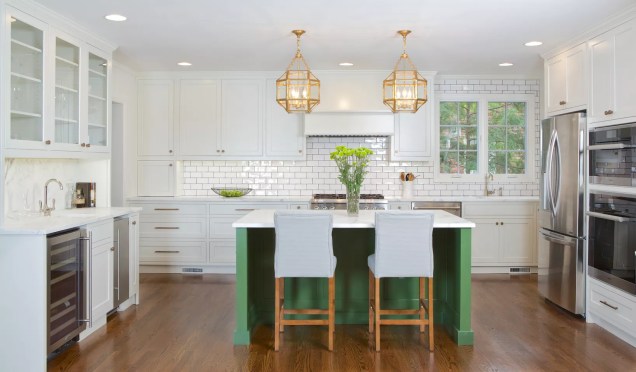 Uma ilha de cozinha verde adiciona cores brilhantes a esta cozinha neutra da Copper Sky Renovations. Dois outros itens que valem a pena serem mencionados são as luminárias de ferro dourado que dão brilho ao espaço.