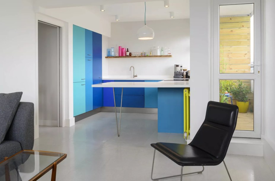 17-38-jeitos-de-incorporar-cor-na-sua-cozinha Quem disse que uma cozinha minimalista deve ser fria e rígida? Esta cozinha minúscula criada pelo Brian O'Tuama Architecture apresenta armários frontais planos em vários tons de azul. Um radiador verde-limão ajuda a pontuar o ambiente.