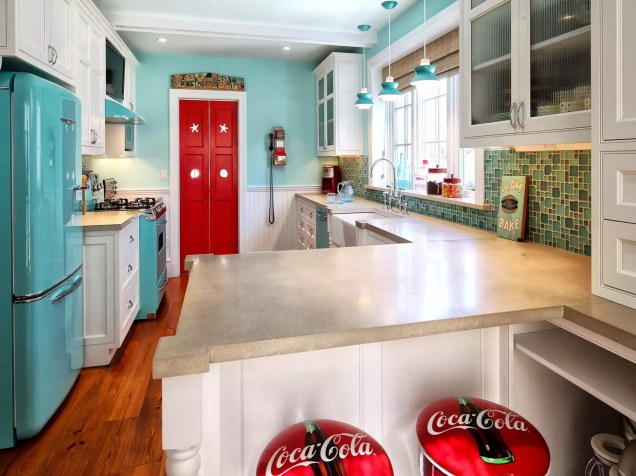 Uma casa de praia em Cape May, New Jersey, passou por uma nova reforma retrô da Knight Architects. Os novos eletrodomésticos turquesa realçam a cozinha com uma cor alegre. Enquanto isso, as portas vermelhas e os bancos da Coca-Cola são achados felizes.