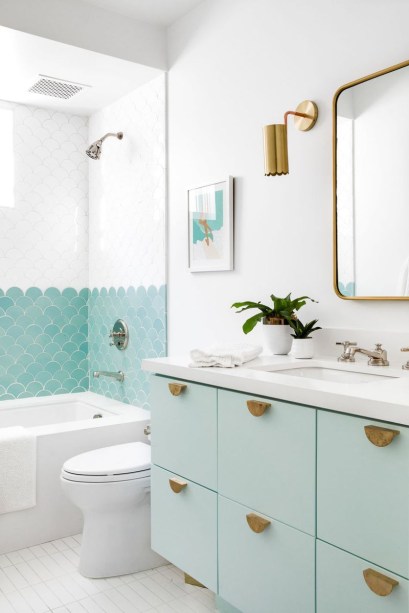 20-ideias-criativas-de-banheiros-com-azulejos-06 <span style="font-weight: 400">A forma recortada deste revestimento de cerâmica, combinada com a tonalidade verde menta, fornece vibrações retrô. A atenção aos detalhes complementares, como puxadores de gaveta arredondados e arandelas recortadas, deixa tudo ainda mais especial.</span>