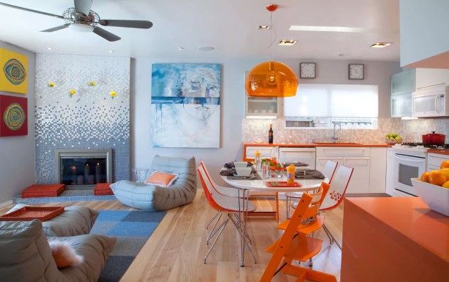 O laranja assumiu o comando desta renovação da cozinha por Kristy Kropat Interior Design. Uma bancada de superfície e pia da mesa injetam o espaço com tons cítricos deliciosos. Sobre a mesa da cozinha está um abajur, cujo acrílico filtra a luz com um tom laranja.