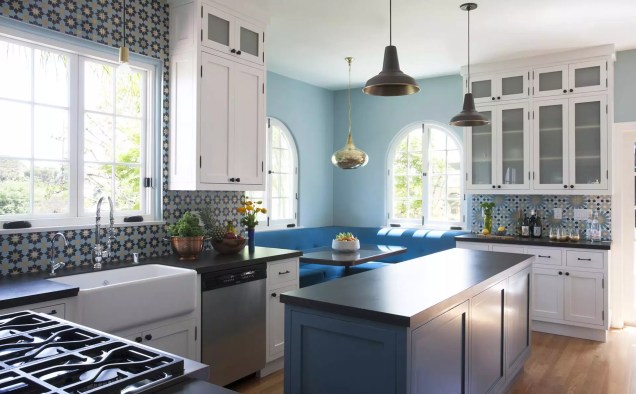Misturar e combinar ladrilhos coloridos é uma maneira inesperada de animar uma cozinha. Veja como exemplo os dois backsplashes diferentes nesta cozinha azul da Vidal Design Collaborative.