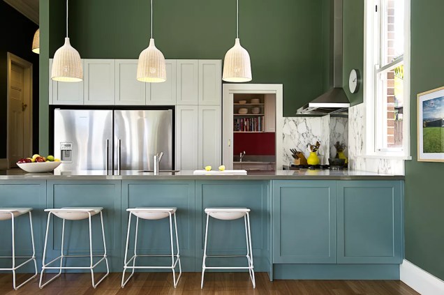 Nesta casa australiana assinada por Brett Mickan Interior Design, a parede verde envolve o espaço com cor, ao mesmo tempo que tem um efeito recuado que define o tom para os acessórios de cozinha em branco e azul.