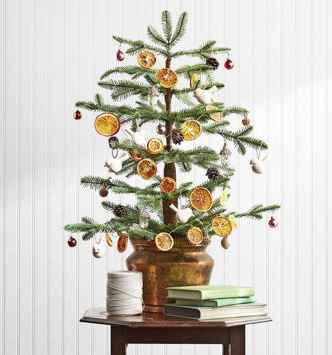 Menos é mais nesta árvore de Natal coberta por enfeites de pinhas e laranjas, que dão um toque orgânico à decoração.