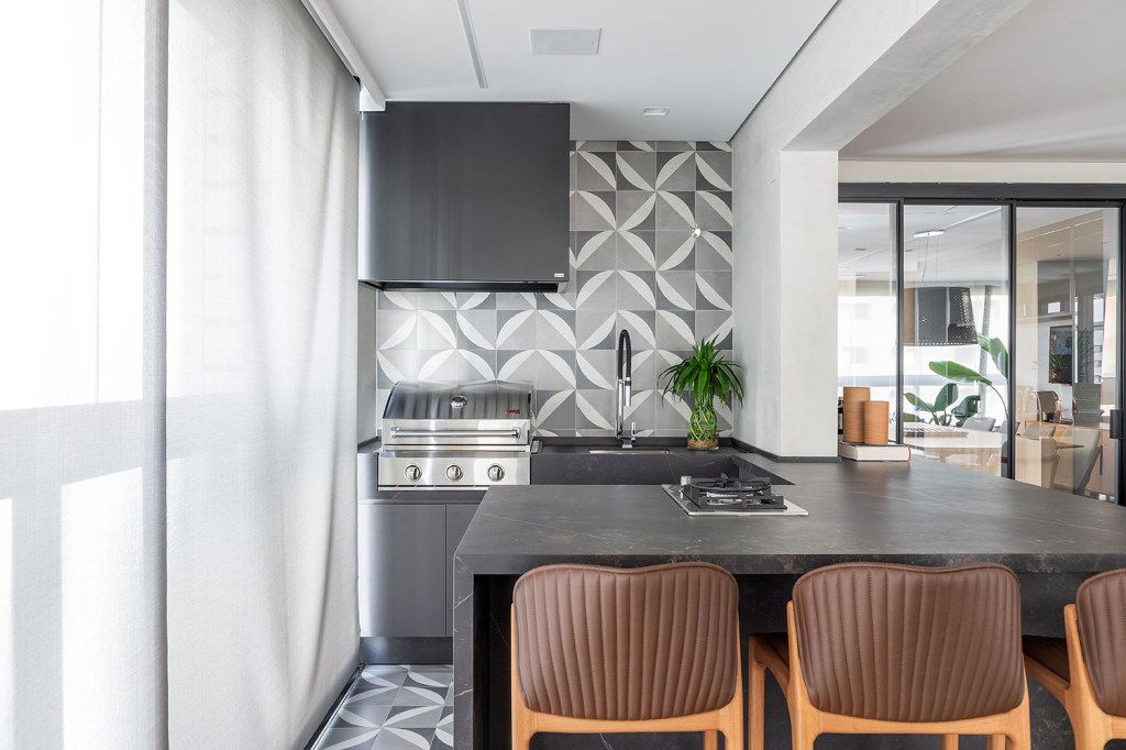 apartamento-ganha-atmosfera-clean-e-paleta-de-tons-neutros-casa.com-andre-bustamante-rafael-renzo-38 Varanda gourmet com churrasqueira e bancada com duas banquetas demadeira e estofado de couro marrom