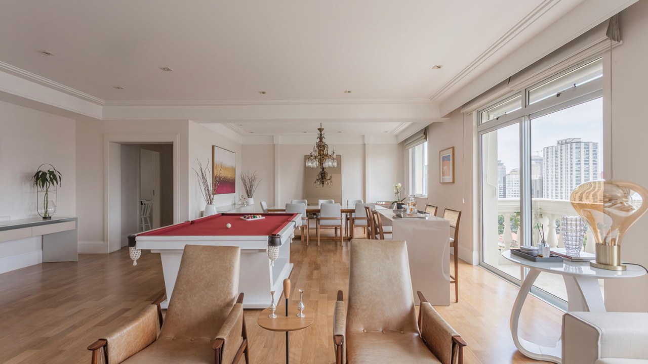 Duas poltrona de couro marrom na sala de estar, de costas para a mesa de sinuca, que fica no centro da sala,por Gabriela Casagrande Arquitetura
