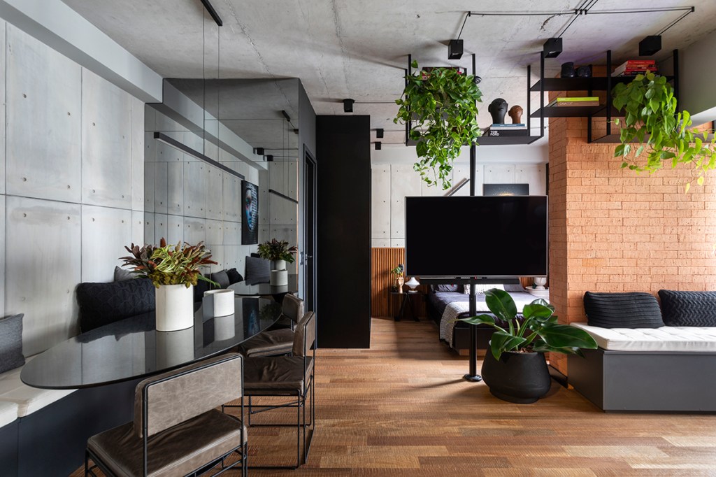 Sala de estar integrada com piso de madeira e plantas suspensas