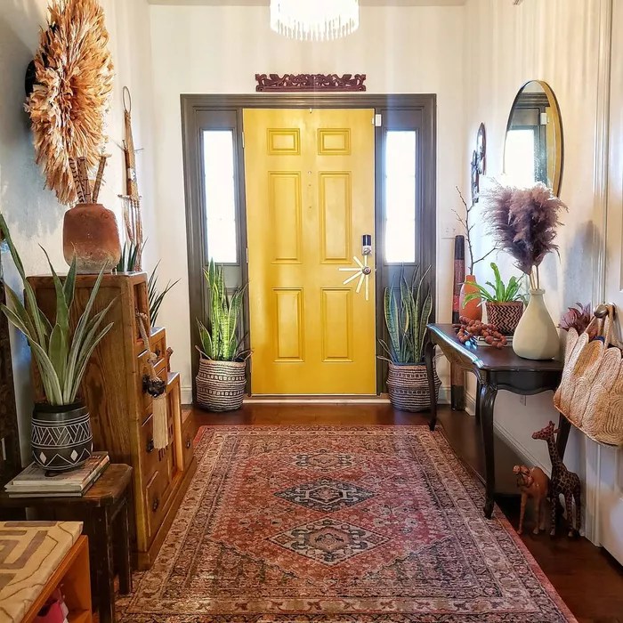 Hall de entrada com porta amarela, tapete vintage e aparador