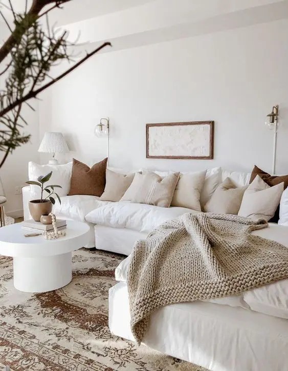 Sala de estar com sofá branco exibindo almofadas e mantas
