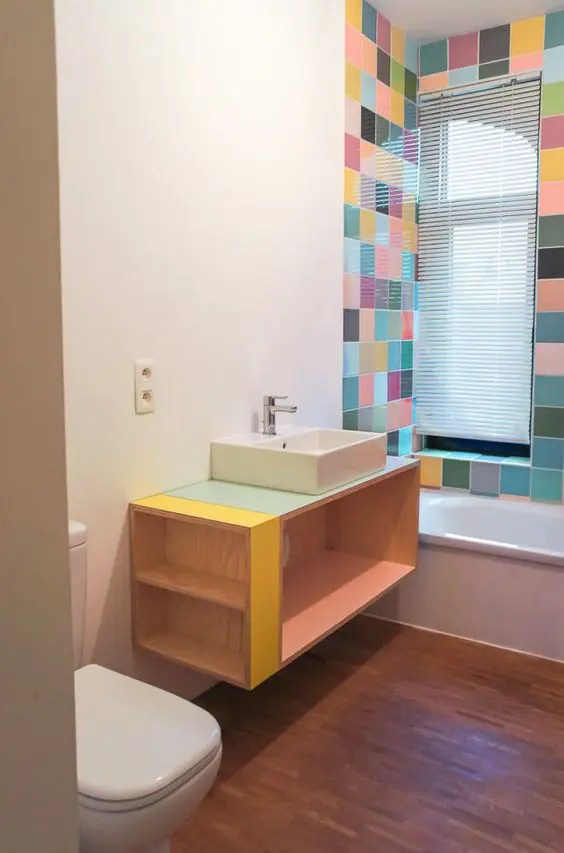 Azulejos arrojados ao redor da banheira e uma penteadeira flutuante com toques coloridos fazem parte deste ambiente