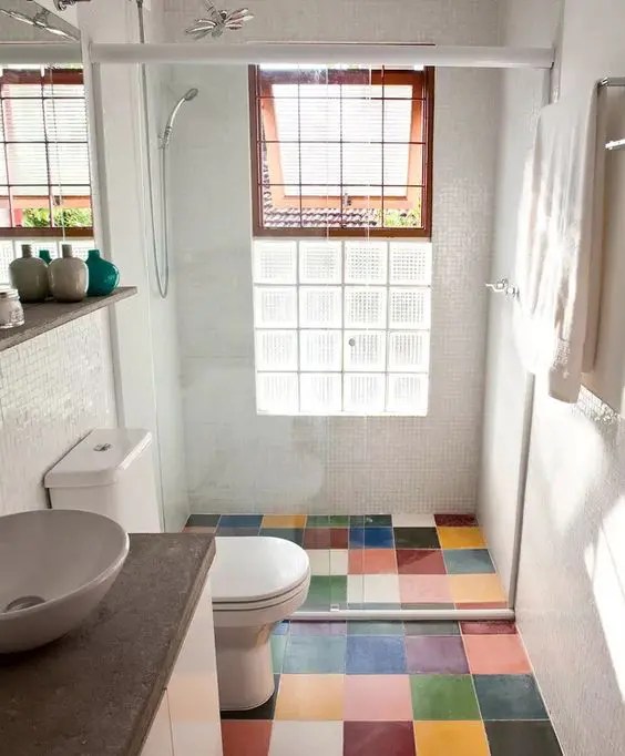 Banheiro moderno com piso de ladrilhos multicoloridos e uma penteadeira com bancada de pedra